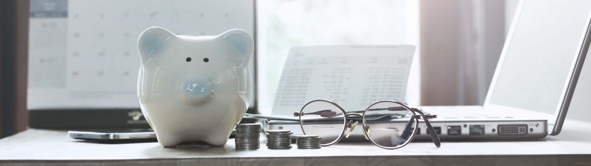 Finance desk with piggy bank, glasses and laptop